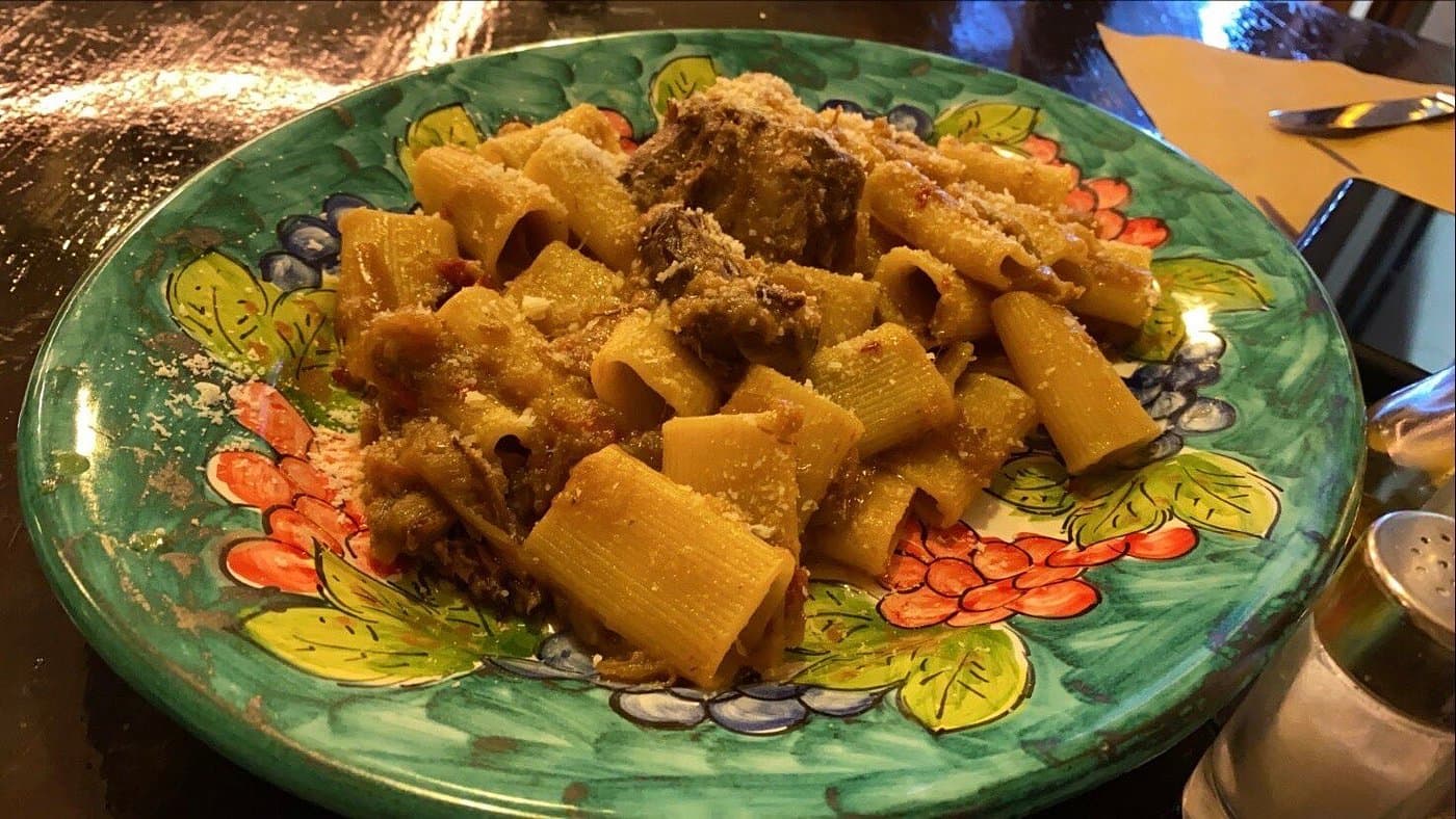 Rigatoni con carne serviti su un piatto decorato
